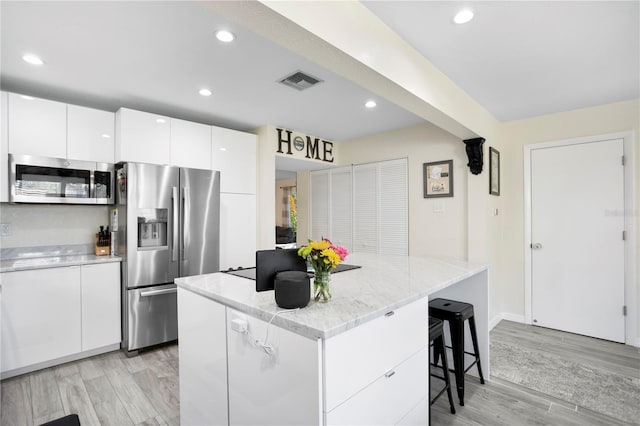 kitchen featuring a breakfast bar, visible vents, white cabinets, appliances with stainless steel finishes, and modern cabinets