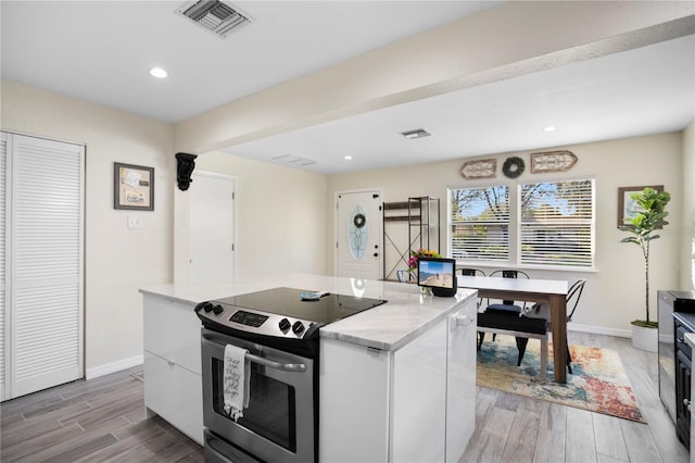 kitchen featuring light wood-style flooring, visible vents, electric range, and baseboards