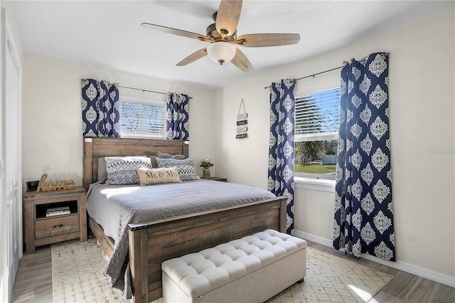 bedroom featuring a ceiling fan, baseboards, and wood finished floors