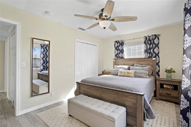 bedroom featuring a closet, visible vents, a ceiling fan, wood finished floors, and baseboards