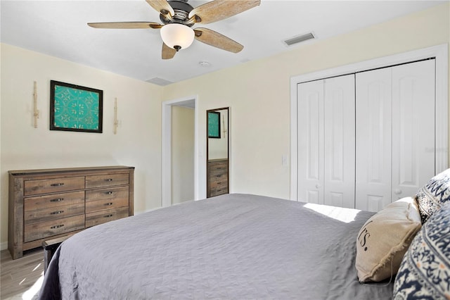 bedroom featuring a ceiling fan, a closet, visible vents, and wood finished floors