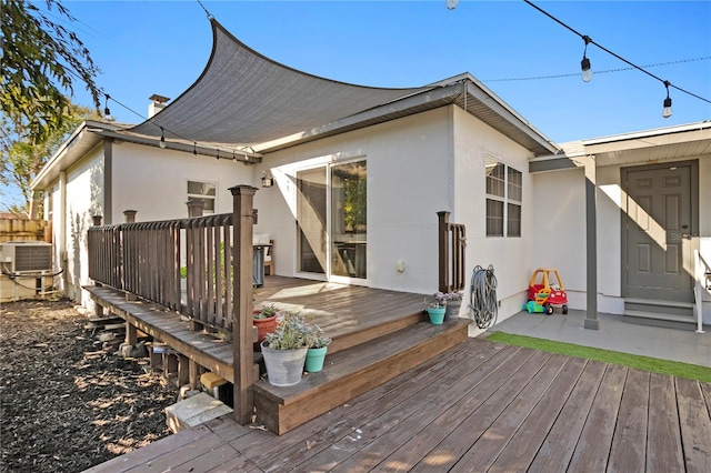 rear view of property with central AC, a deck, and stucco siding