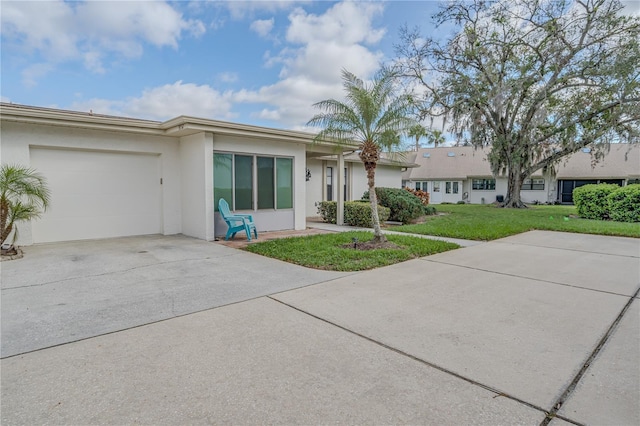 ranch-style home featuring a garage, a front lawn, concrete driveway, and stucco siding