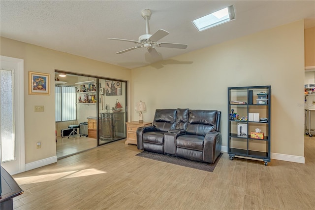 living area with light wood-style flooring, baseboards, ceiling fan, and a textured ceiling