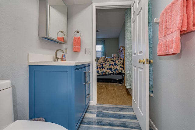 bathroom featuring baseboards, toilet, wood finished floors, ensuite bathroom, and vanity