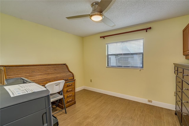 home office with baseboards, light wood-style flooring, a ceiling fan, and a textured ceiling