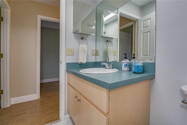 bathroom with wood tiled floor, vanity, and baseboards