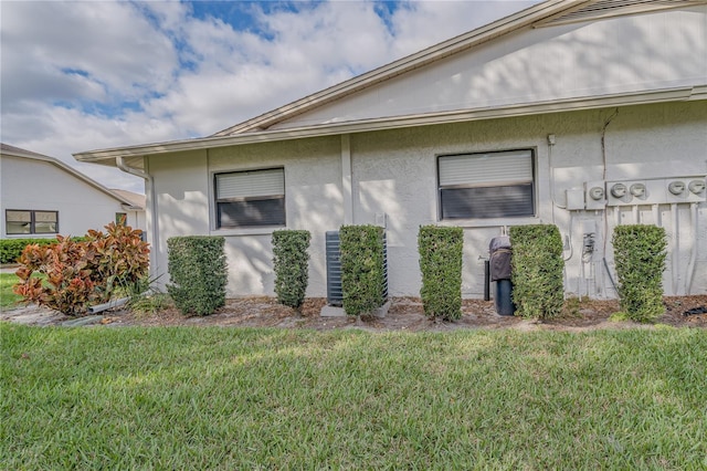 view of side of home with stucco siding and a yard