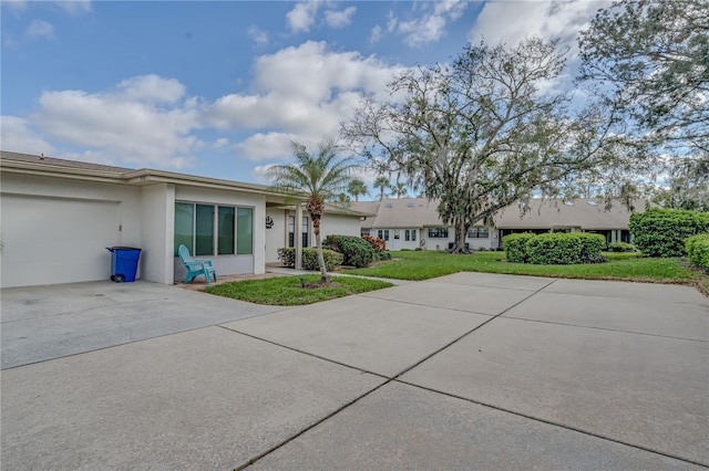 view of front of home with a garage, a front yard, concrete driveway, and stucco siding