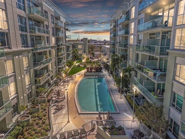 pool at dusk with a community pool, fence, and a patio