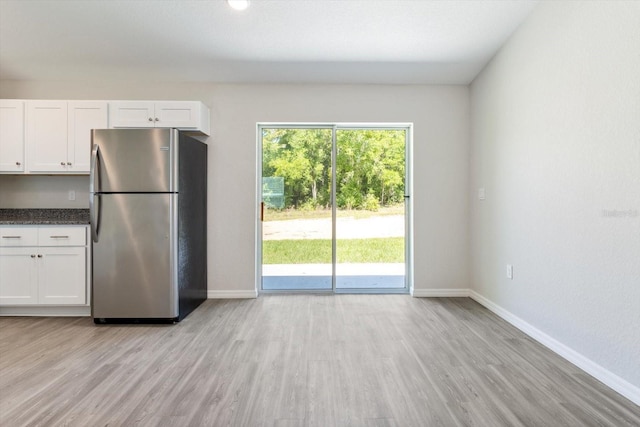 kitchen featuring dark countertops, baseboards, white cabinets, and freestanding refrigerator