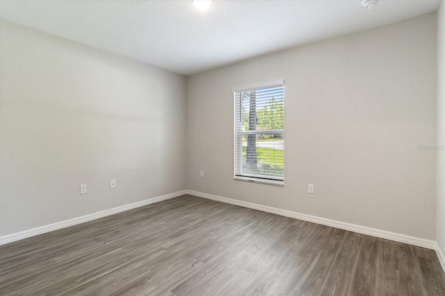 spare room with dark wood-style floors and baseboards