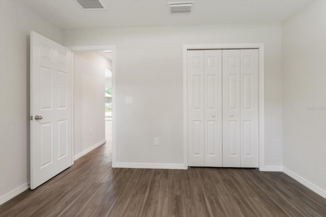 unfurnished bedroom with dark wood-style floors, baseboards, and visible vents