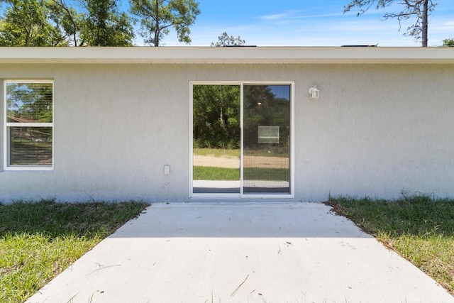 doorway to property with a patio area and stucco siding