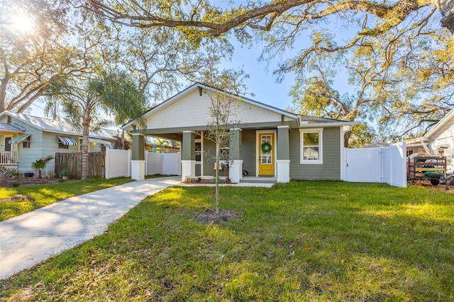 bungalow-style house with covered porch, a front yard, a gate, fence, and driveway