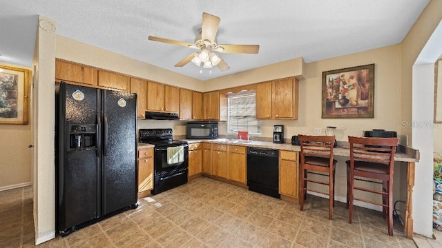 2453 Teri St, Auburndale, FL 33823 - kitchen featuring light countertops, a ceiling fan, brown cabinetry, under cabinet range hood, and black appliances