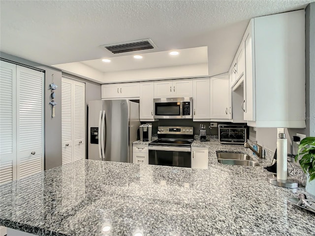 kitchen featuring appliances with stainless steel finishes, a sink, visible vents, and white cabinets