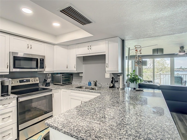 kitchen with stainless steel appliances, a sink, visible vents, and white cabinets