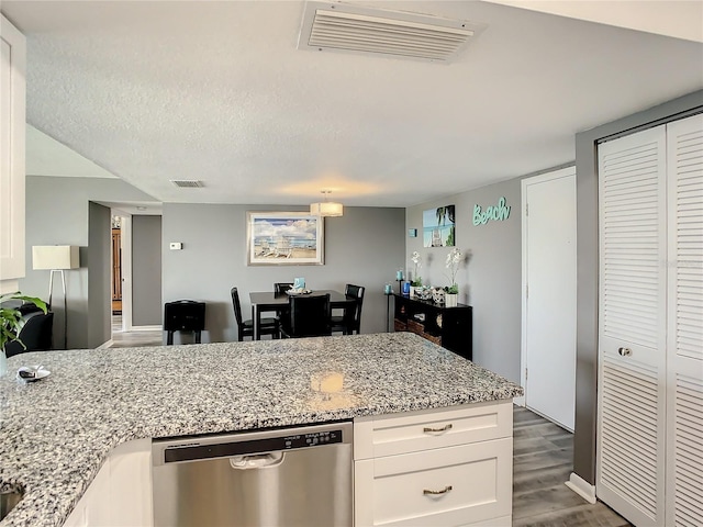 kitchen with light stone countertops, white cabinetry, visible vents, and stainless steel dishwasher