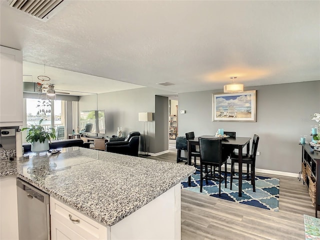 kitchen featuring baseboards, white cabinets, light stone counters, light wood-type flooring, and stainless steel dishwasher