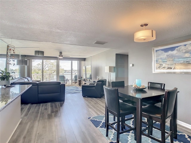 dining area featuring a ceiling fan, a textured ceiling, baseboards, and wood finished floors