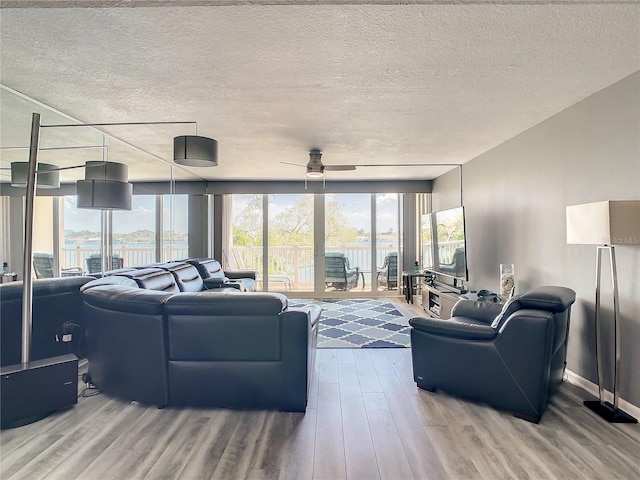 living room featuring floor to ceiling windows, ceiling fan, a textured ceiling, wood finished floors, and baseboards