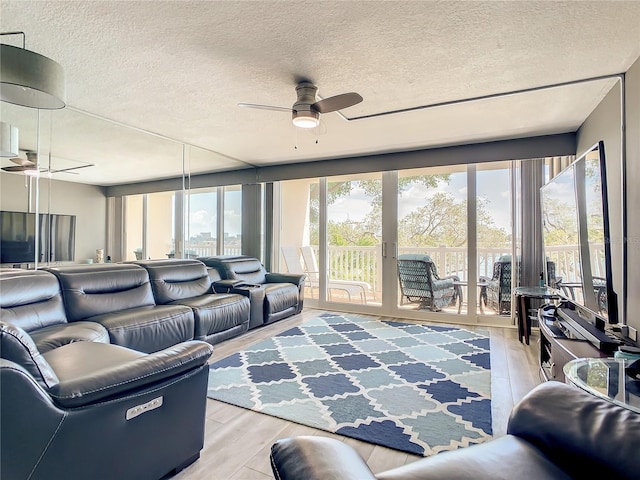 living area featuring light wood-type flooring, a ceiling fan, and a wealth of natural light