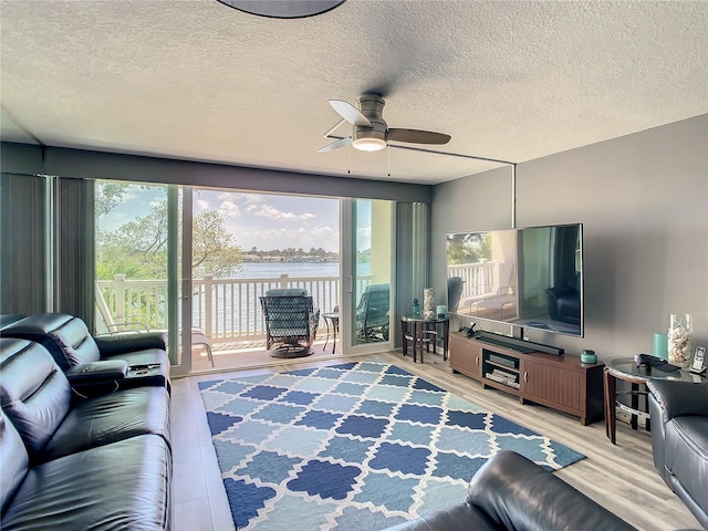 living area with ceiling fan, a textured ceiling, and wood finished floors