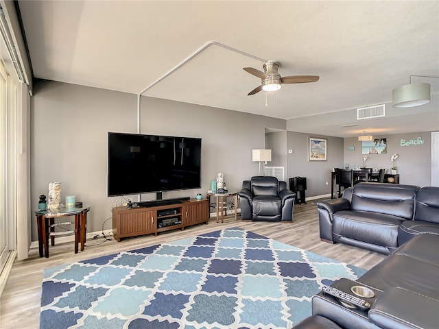 living room with baseboards, ceiling fan, visible vents, and wood finished floors