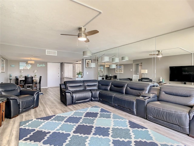 living area with wood finished floors, visible vents, and a ceiling fan