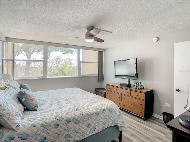 bedroom with baseboards, ceiling fan, light wood-style flooring, and a textured ceiling