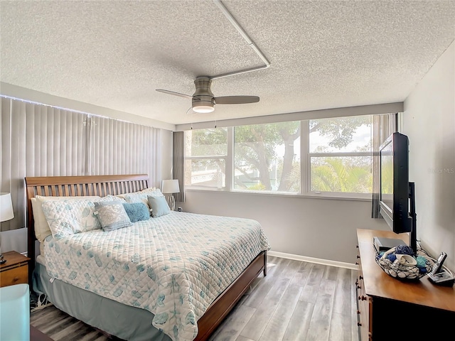 bedroom with a textured ceiling, light wood finished floors, multiple windows, and baseboards