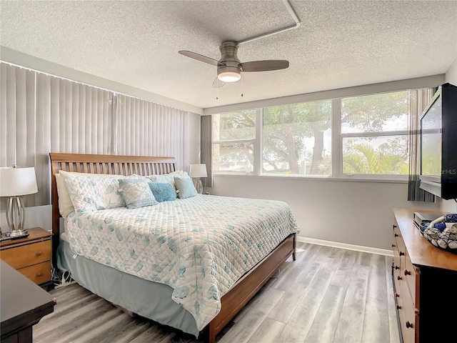 bedroom featuring light wood-style floors, multiple windows, and a textured ceiling