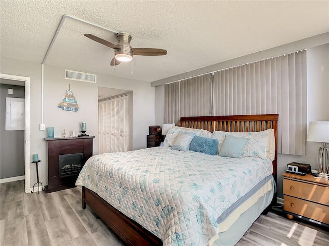 bedroom featuring a textured ceiling, ceiling fan, wood finished floors, and visible vents