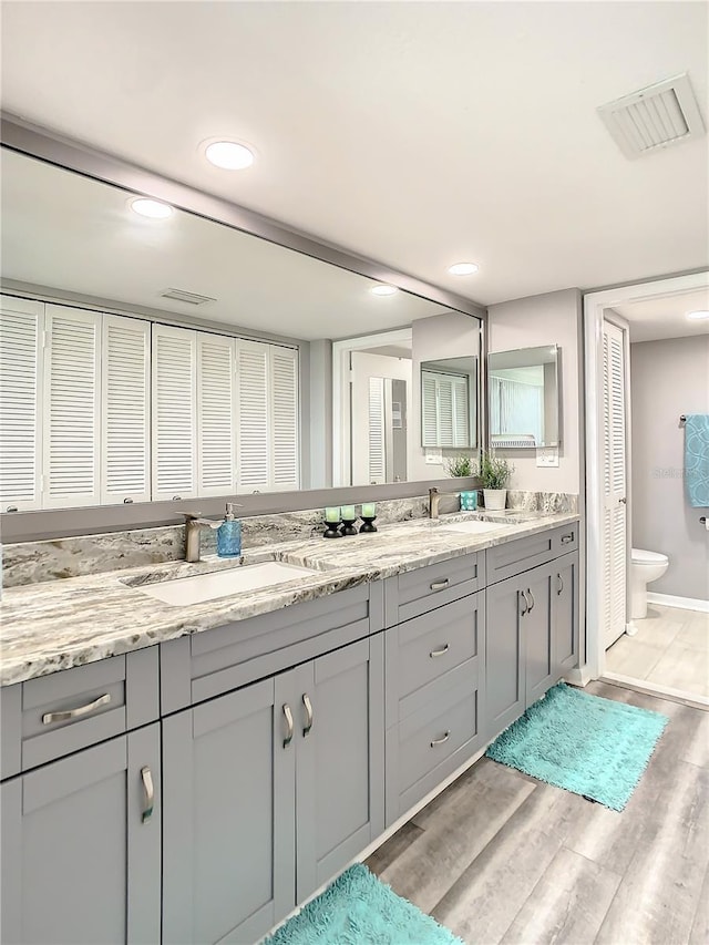 full bath featuring a closet, visible vents, a sink, and wood finished floors