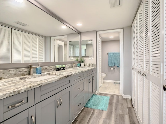 bathroom with double vanity, a closet, visible vents, a sink, and wood finished floors