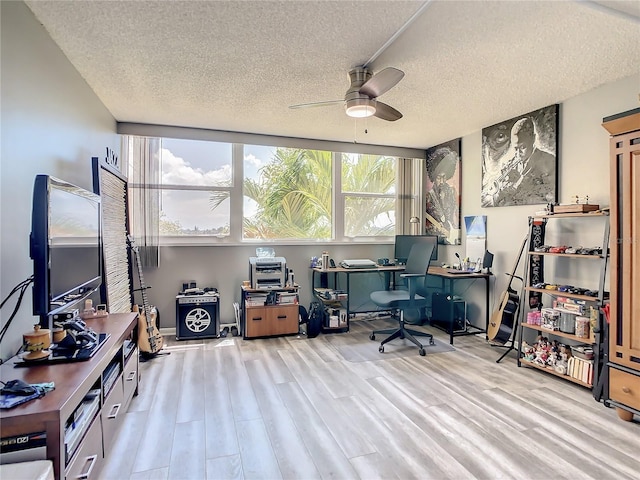 office area with a ceiling fan, light wood-style flooring, and a textured ceiling