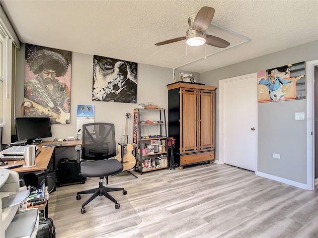 office space featuring baseboards, ceiling fan, a textured ceiling, and light wood finished floors