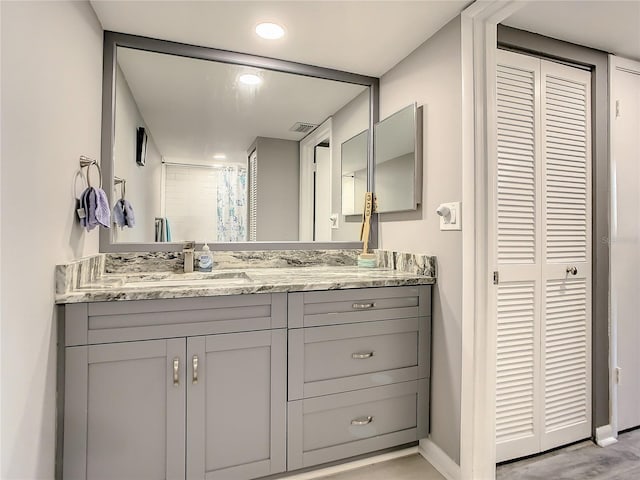 bathroom featuring a shower with shower curtain, baseboards, a closet, and vanity