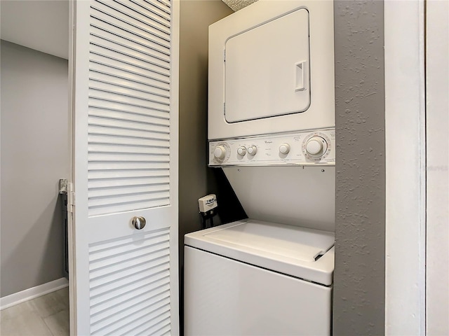 laundry area with stacked washer / dryer, laundry area, and baseboards