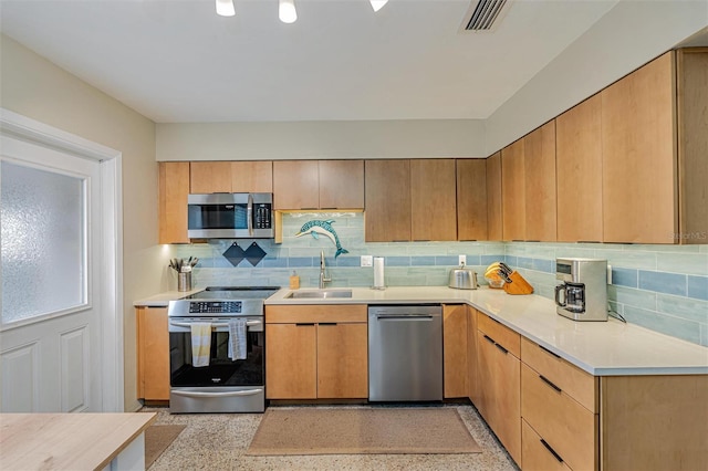 kitchen with a sink, stainless steel appliances, light countertops, and light speckled floor