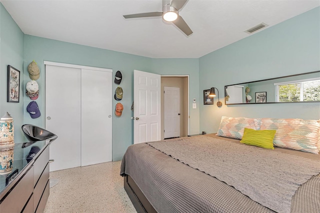 bedroom featuring light speckled floor, a closet, visible vents, and a ceiling fan