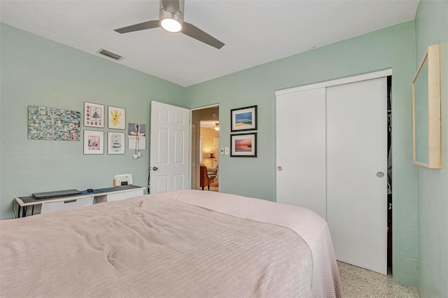 bedroom with a ceiling fan, visible vents, light speckled floor, and a closet