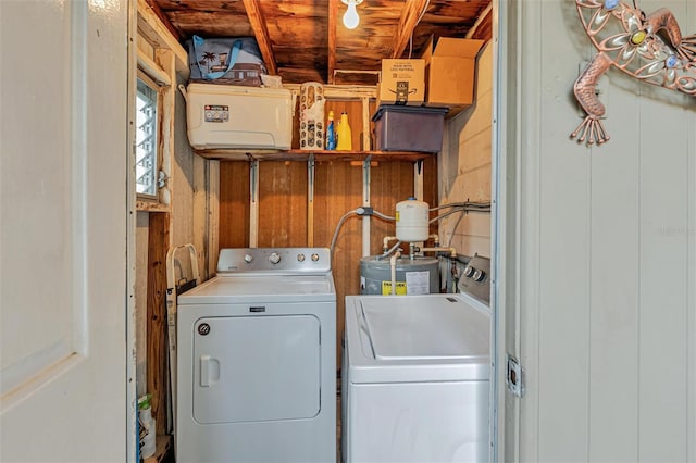 clothes washing area with laundry area, wood walls, and washer and dryer