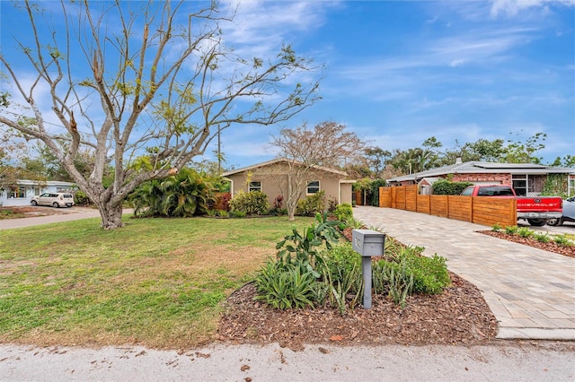 view of front of house with driveway, fence, and a front lawn