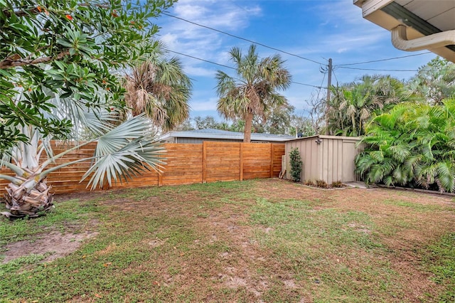 view of yard with an outbuilding, a fenced backyard, and a shed