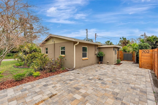 rear view of property featuring a patio, fence, and stucco siding