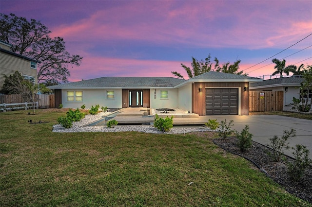 single story home with stucco siding, concrete driveway, fence, a garage, and a front lawn