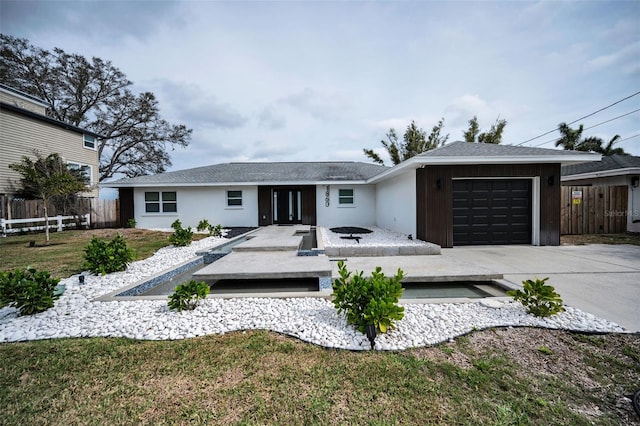 ranch-style house with driveway, an attached garage, fence, a front lawn, and stucco siding