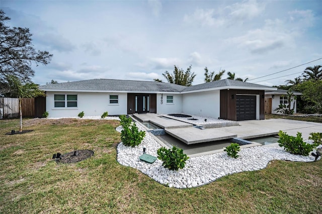 view of front of property featuring a garage, driveway, a hot tub, fence, and a front lawn